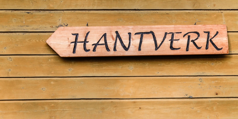 Träskylt med texten 'HANTVERK' på en trävägg.