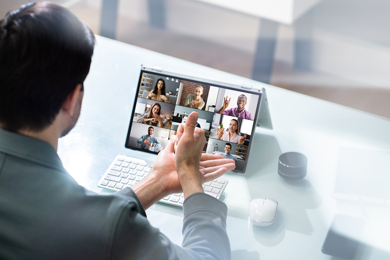 En person deltar i ett videomöte vid en bärbar dator med flera personer synliga på skärmen.