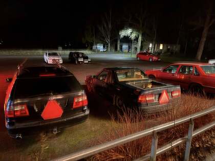 Flera bilar står parkerade på en mörk parkeringsplats, alla med röda trianglar bakpå.