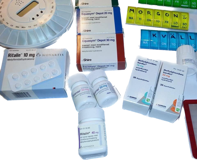 Olika medicinförpackningar, dosett och läkemedelsburkar på ett bord, ingen människa syns.