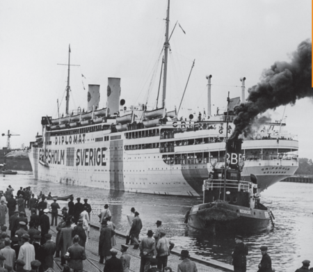 Svartvit bild av ett stort fartyg märkt 'Sverige' och 'Diplomat', med många människor på kajen.