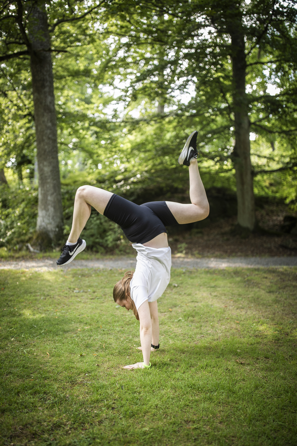 En person gör en handvolt på gräset i en grönskande park.