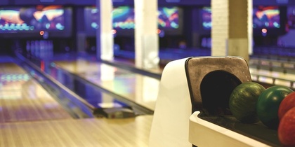 En bowlinghall med flera bowlingbanor och färgglada bowlingklot i förgrunden.