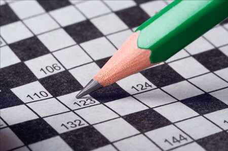 En grön blyertspenna pekar på en ruta i ett korsord med siffror.