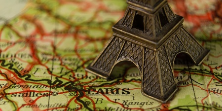 Närbild av en liten Eiffeltorn-modell placerad på en karta över Paris, Frankrike.