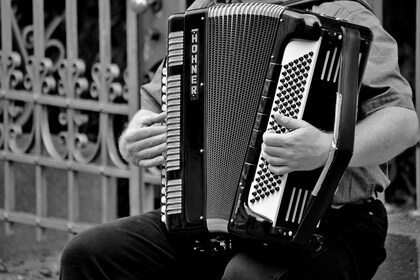 En person spelar dragspel utomhus, bilden är i svartvitt och visar endast överkroppen och instrumentet.