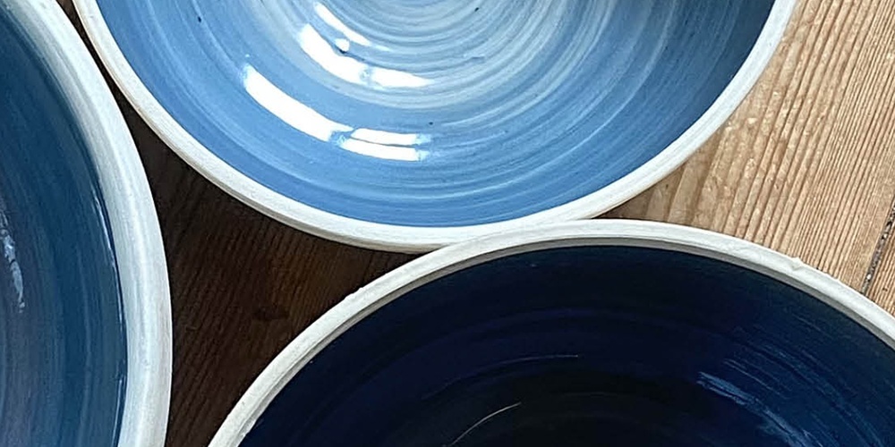 Tre blå keramikskålar på ett trägolv med texten 'Prova på: Keramik' ovanpå.