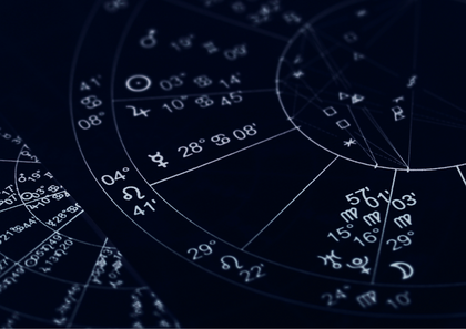 Närbild av ett astrologiskt födelsediagram med zodiaksymboler och grader mot mörk bakgrund.