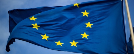Europeiska unionens flagga med tolv gula stjärnor på blå bakgrund vajar mot en blå himmel.