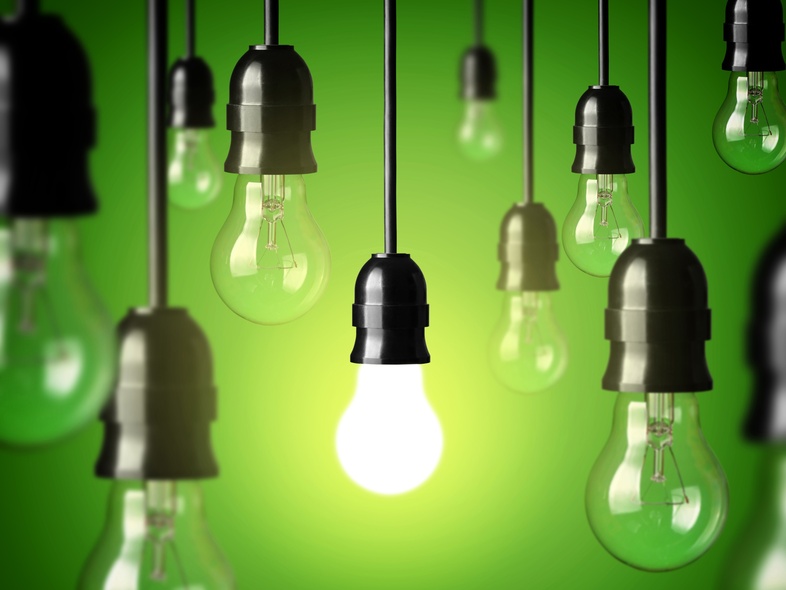 Flera hängande glödlampor mot grön bakgrund, en lampa lyser medan resten är släckta.