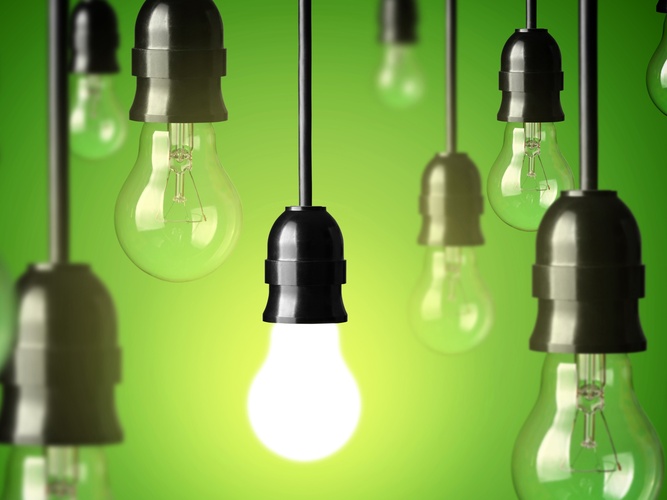 Flera hängande glödlampor mot grön bakgrund, en lampa lyser medan resten är släckta.