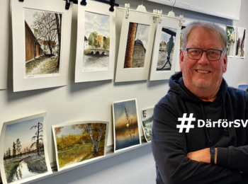 Leende man står framför en vägg med akvarellmålningar i ett konstgalleri.
