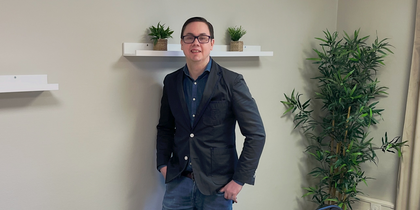 En person står vid väggen i ett mötesrum med bord, stolar, växter och hyllor med krukväxter.