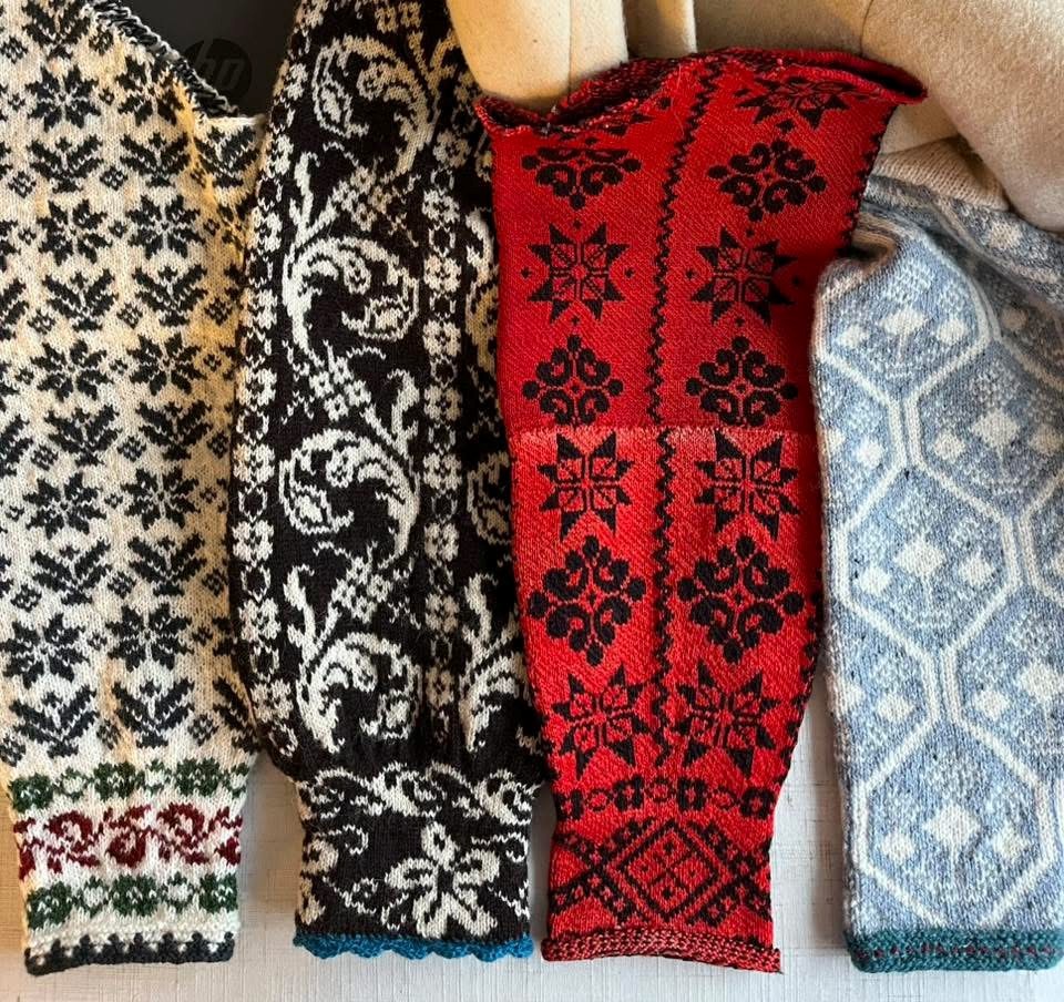 Fyra stickade ärmar med traditionella mönster i svartvitt, rött och blått ligger sida vid sida.