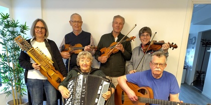Sex personer spelar olika musikinstrument i ett rum, ansiktena är suddade för anonymitet.