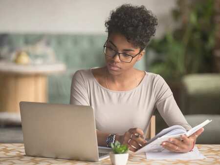 Ung kvinna sitter framför laptop och arbetar.