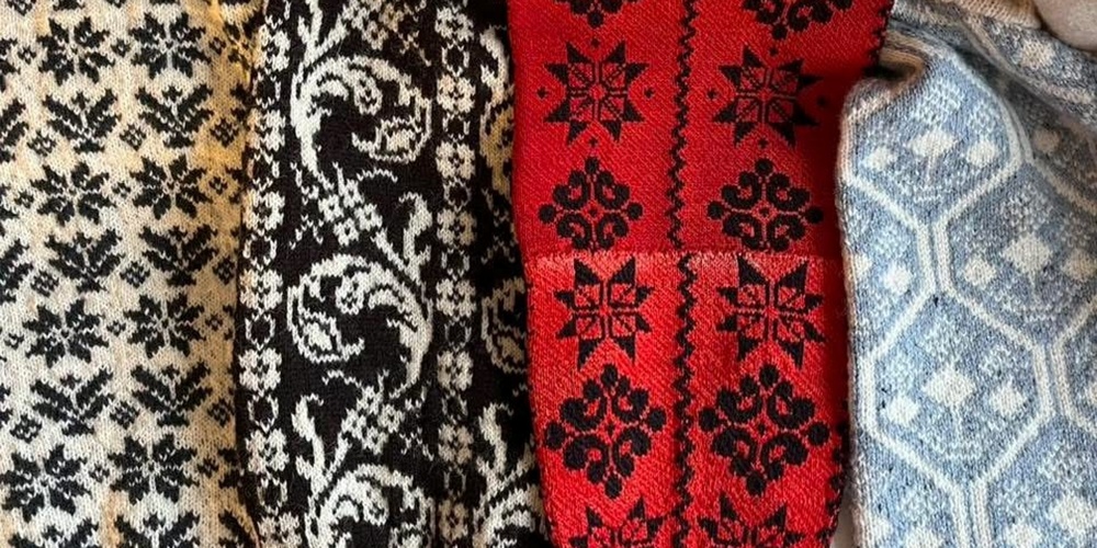 Fyra stickade ärmar med traditionella mönster i svartvitt, rött och blått ligger sida vid sida.