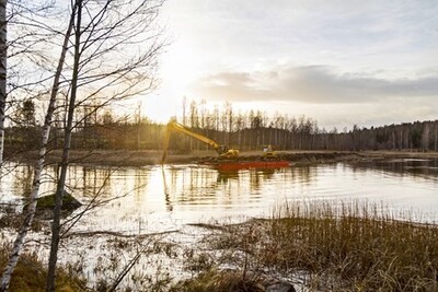 Två personer sitter i en röd båt och fiskar en tidig morgon.