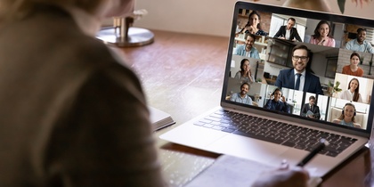 En person deltar i ett videomöte med flera deltagare på en bärbar dator vid ett skrivbord.