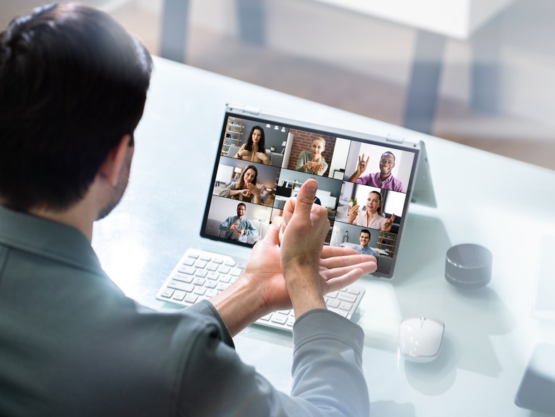 En person deltar i ett videomöte vid en bärbar dator med flera personer synliga på skärmen.