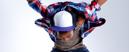 Person i jeans och rutig skjorta hoppar med armar och ben utsträckta mot en ljus bakgrund.