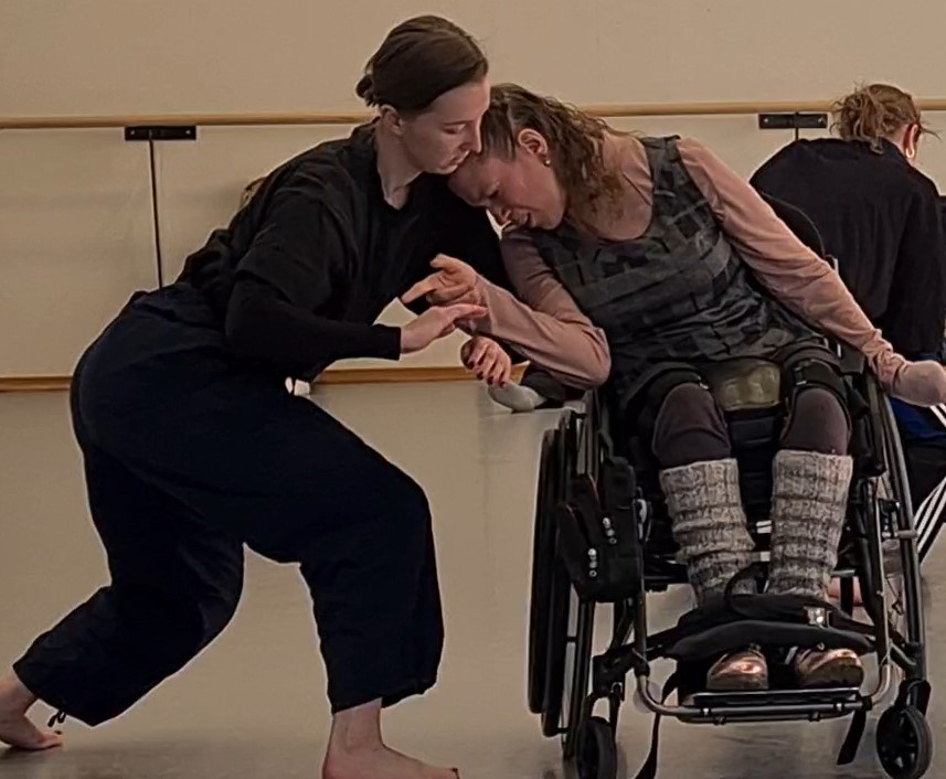 En person i rullstol deltar i en dansövning med en annan person i en dansstudio.