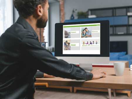 En person sitter vid ett bord fram för en dator och arbetar.