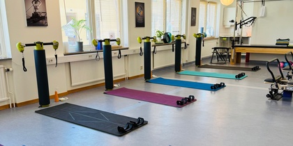 Ljust träningsrum med yogamattor, vikter och träningsutrustning uppställda för gruppträning.