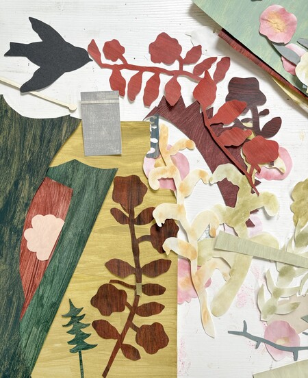 Pappersutklipp i form av blad och blommor i olika färger ligger utspridda på en yta.