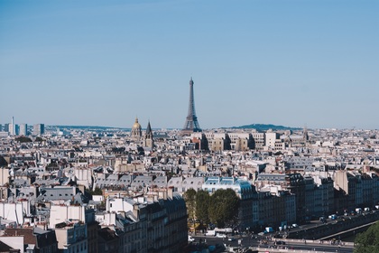 Vy över Paris med Eiffeltornet i centrum under en klarblå himmel.