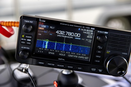 Närbild på en Icom IC-705 amatörradio med färgskärm som visar frekvens och spektrumanalys.