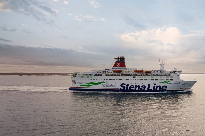 En Stena Line-färja seglar på ett lugnt hav under en molnig himmel vid solnedgång.