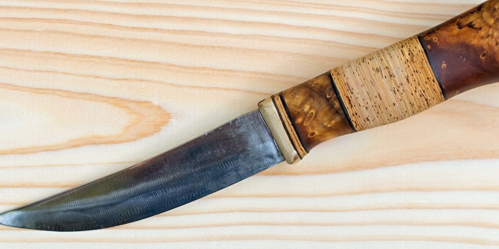 En kniv med trähandtag ligger på en ljus träyta.