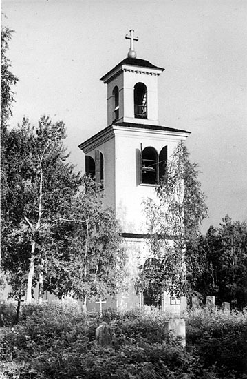 Svartvit bild på en kyrka med klocktorn omgiven av träd och gravstenar.