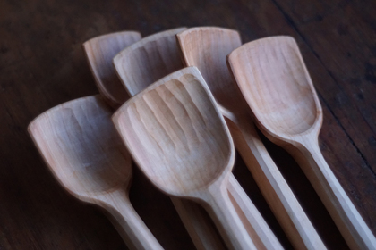 Sex handgjorda träslevar ligger samlade på ett mörkt träbord.