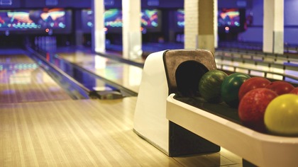 En bowlinghall med flera bowlingbanor och färgglada bowlingklot i förgrunden.