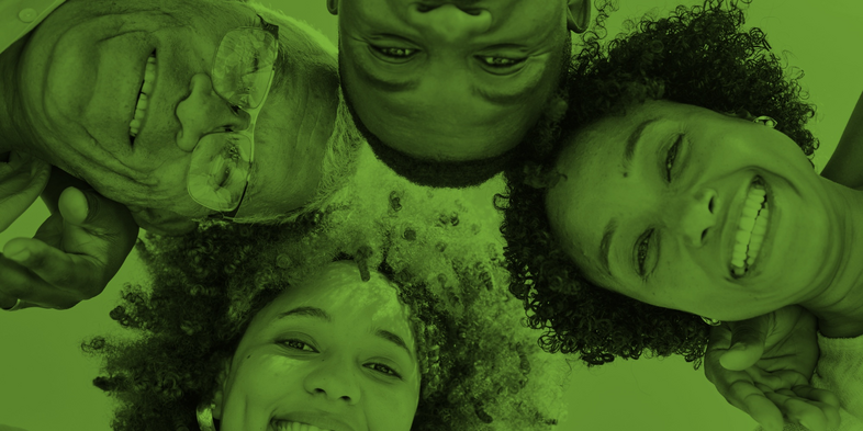 Fyra personer ligger i en cirkel och ler mot kameran, bilden har ett grönt filter.