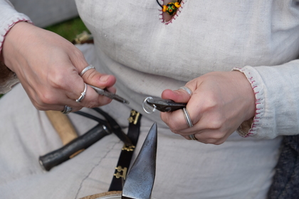 Närbild på händer som arbetar med metallverktyg och ringar, troligen hantverk eller smyckestillverkning.