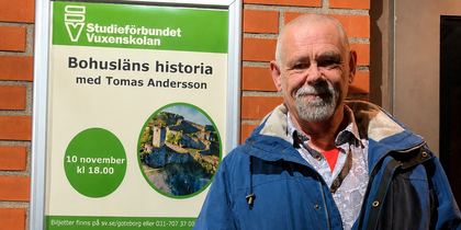 Man i blå jacka står bredvid en affisch om Bohusläns historia på en tegelvägg.
