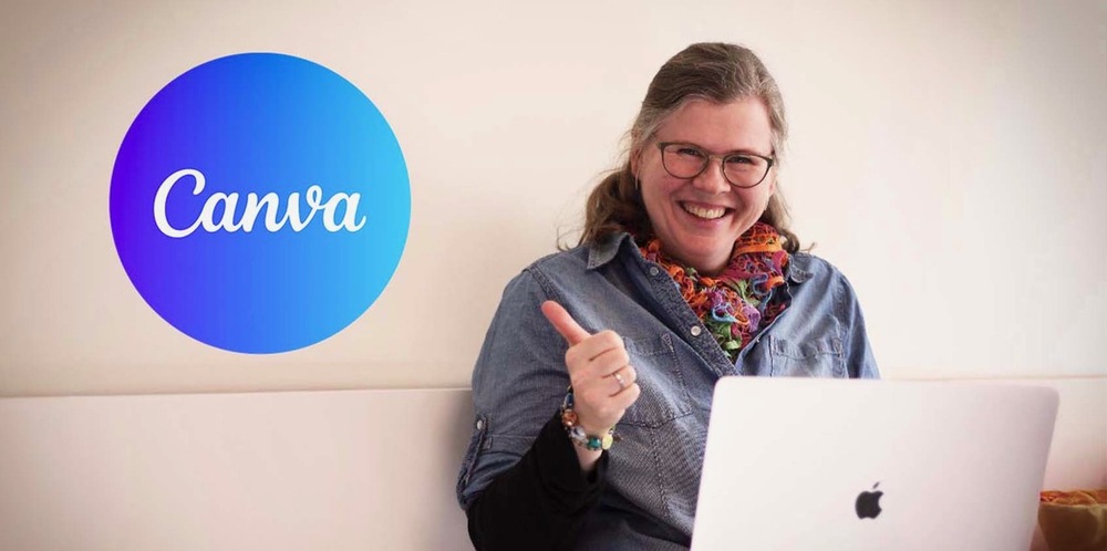 Leende kvinna med glasögon ger tummen upp framför en laptop, Canva-logga syns på väggen.