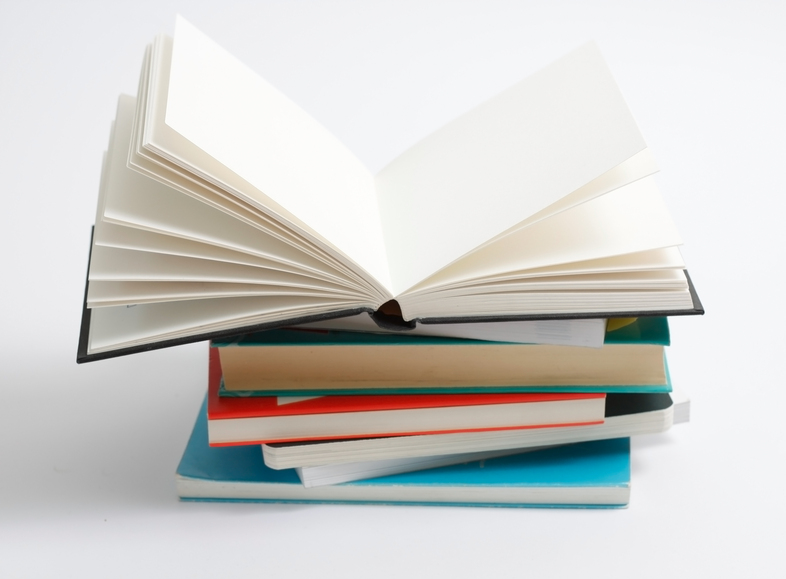 En hög med böcker där den översta boken är uppslagen och resten är stängda, mot vit bakgrund.