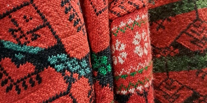 Närbild av röda stickade tröjor med traditionella delsbomönster i grönt, vitt och svart.