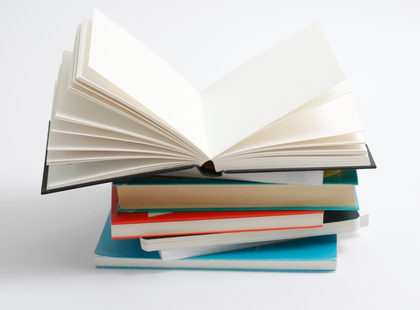 En hög med böcker där den översta boken är uppslagen och resten är stängda, mot vit bakgrund.