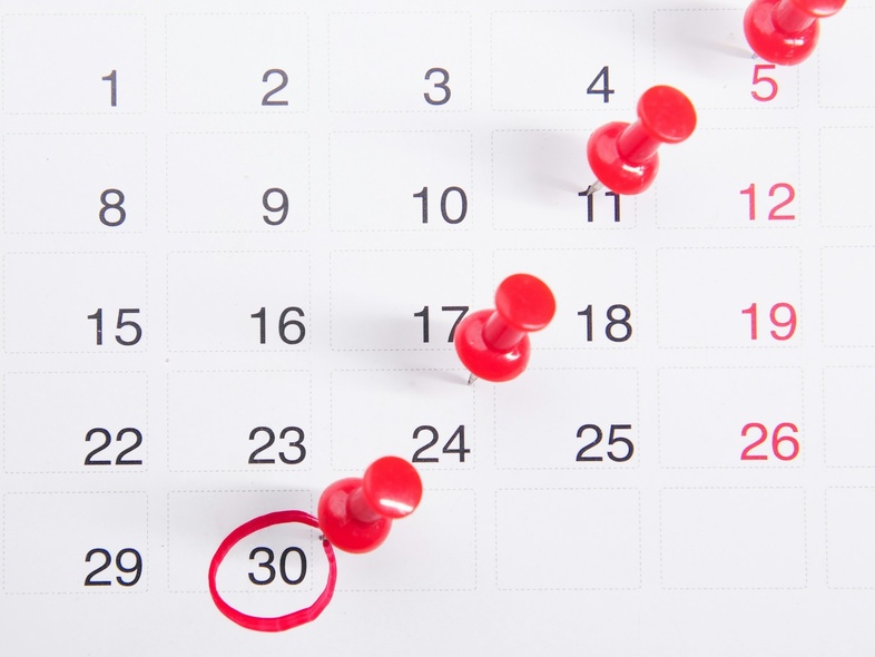 En kalender med röda nålar på vissa datum och den 30:e inringad med röd penna.