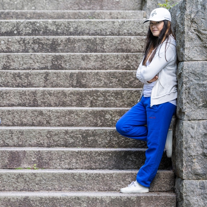 Två personer står lutade mot varsin sida av en bred stentrappa utomhus, klädda i sportkläder och kepsar.