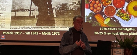 Föreläsningsbild om mjölkprotesterna i Skärholmen 1972 med tidningsurklipp och matvaror från 1970-talet.