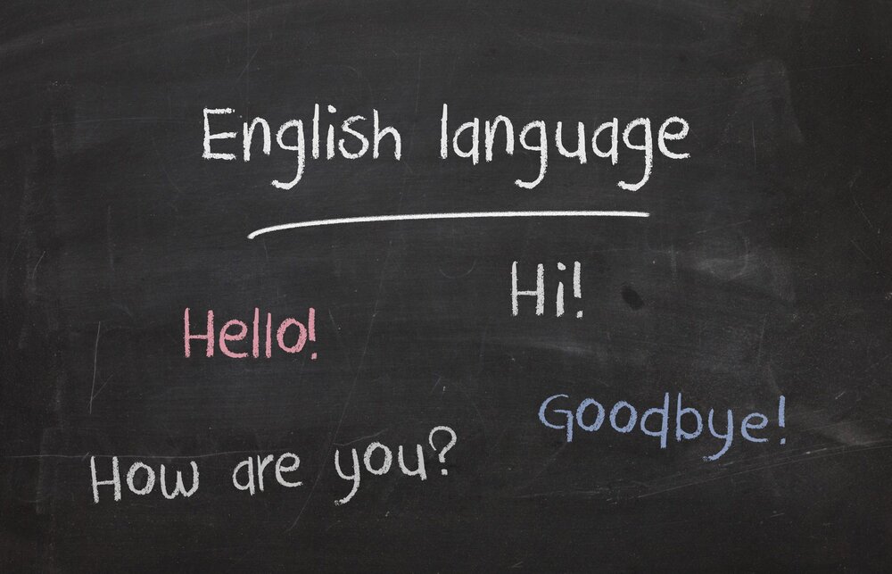 En svart tavla med engelska fraser som 'Hello!', 'Hi!', 'How are you?' och 'Goodbye!' skrivna i olika färger.