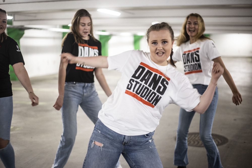 Fyra dansare i parkeringsgarage i Dansstudion-tröjor