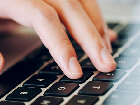 En hand som skriver på ett tangentbord, närbild på fingrar och tangenter.