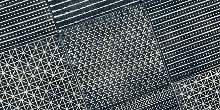 Ett mörkblått och vitt tyg indelat i rutor med olika handtryckta geometriska mönster i japanskinspirerad stil